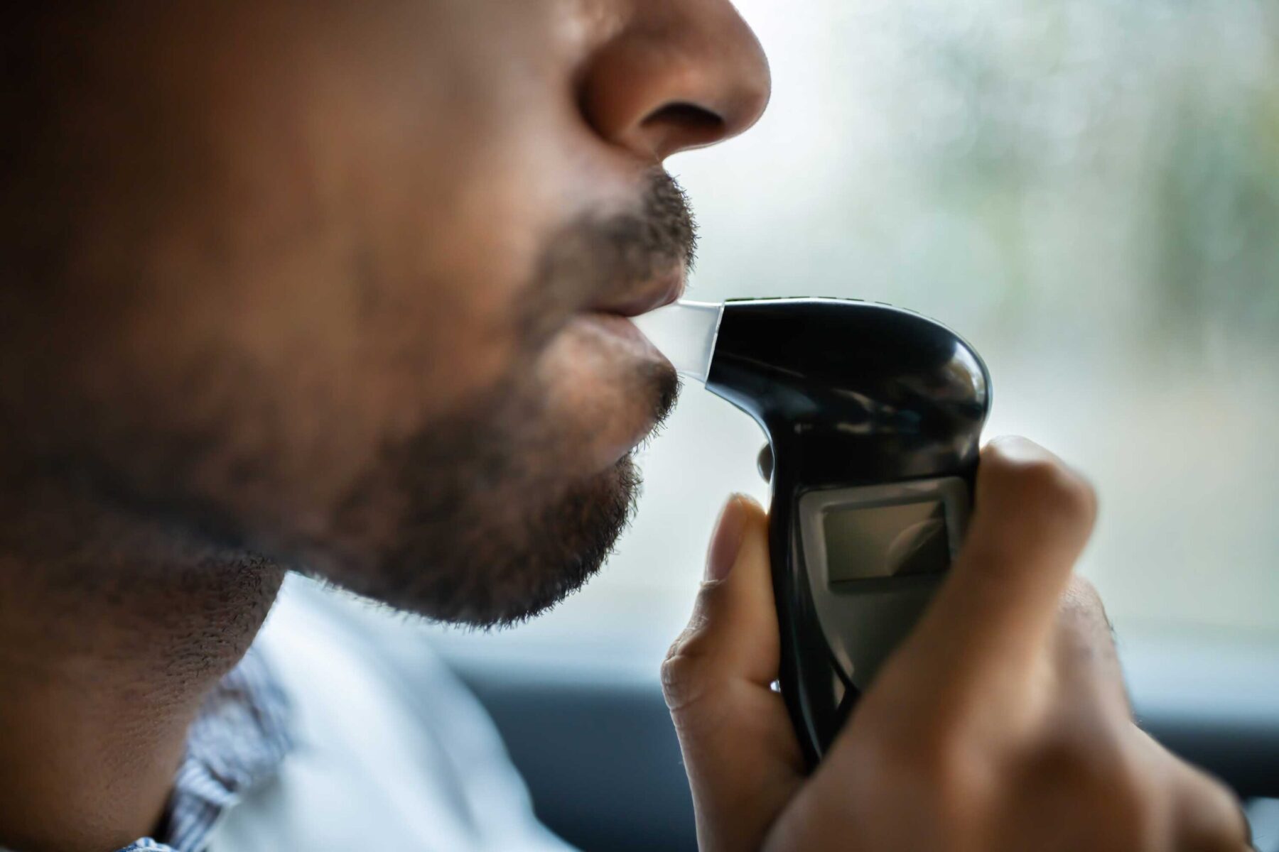 Man blowing into a breathalyzer to rest for drunk driving