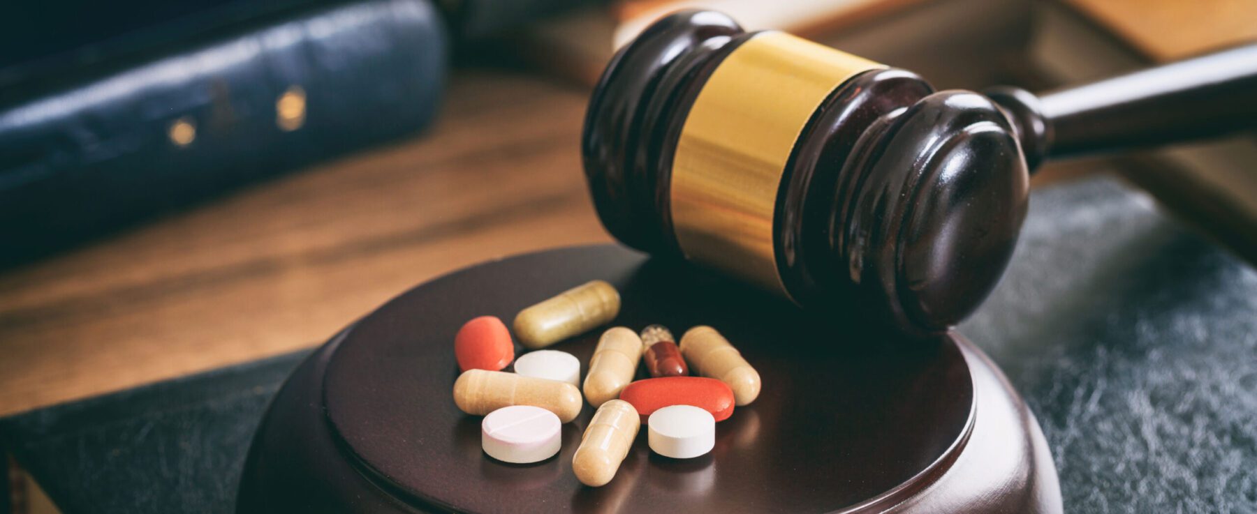 Judge's gavel with pills and drugs next to it