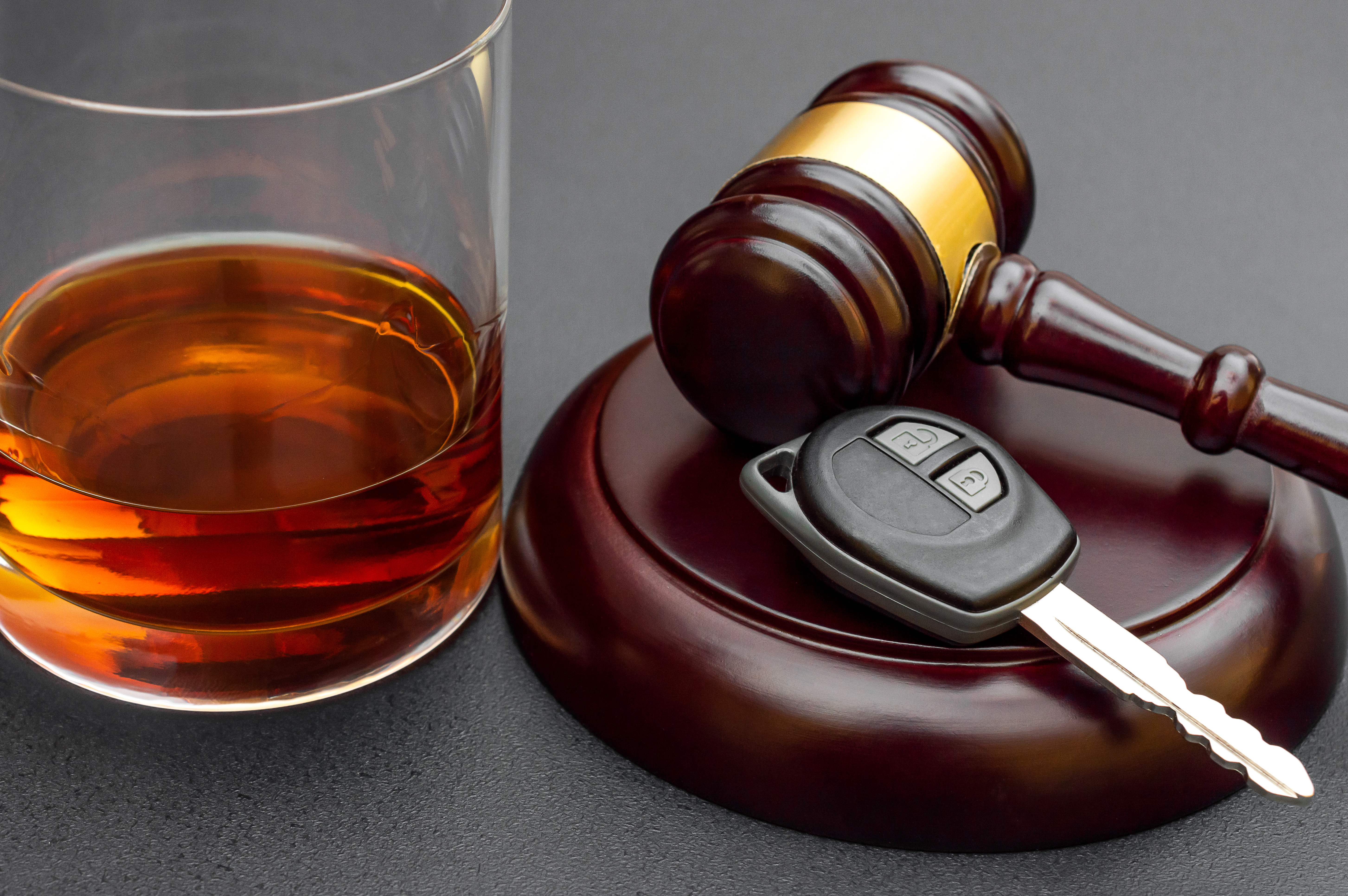 Judge's gavel with car key and glass of whiskey on black background ovi lawyer