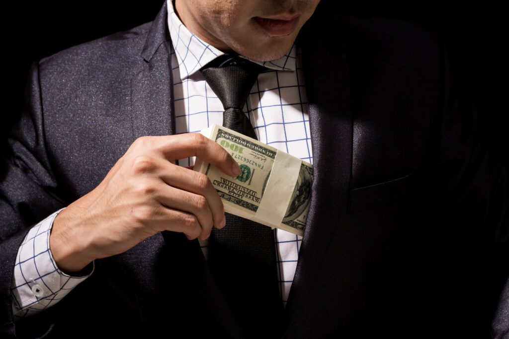 Businessman putting a stack of dollar banknotes into his pocket