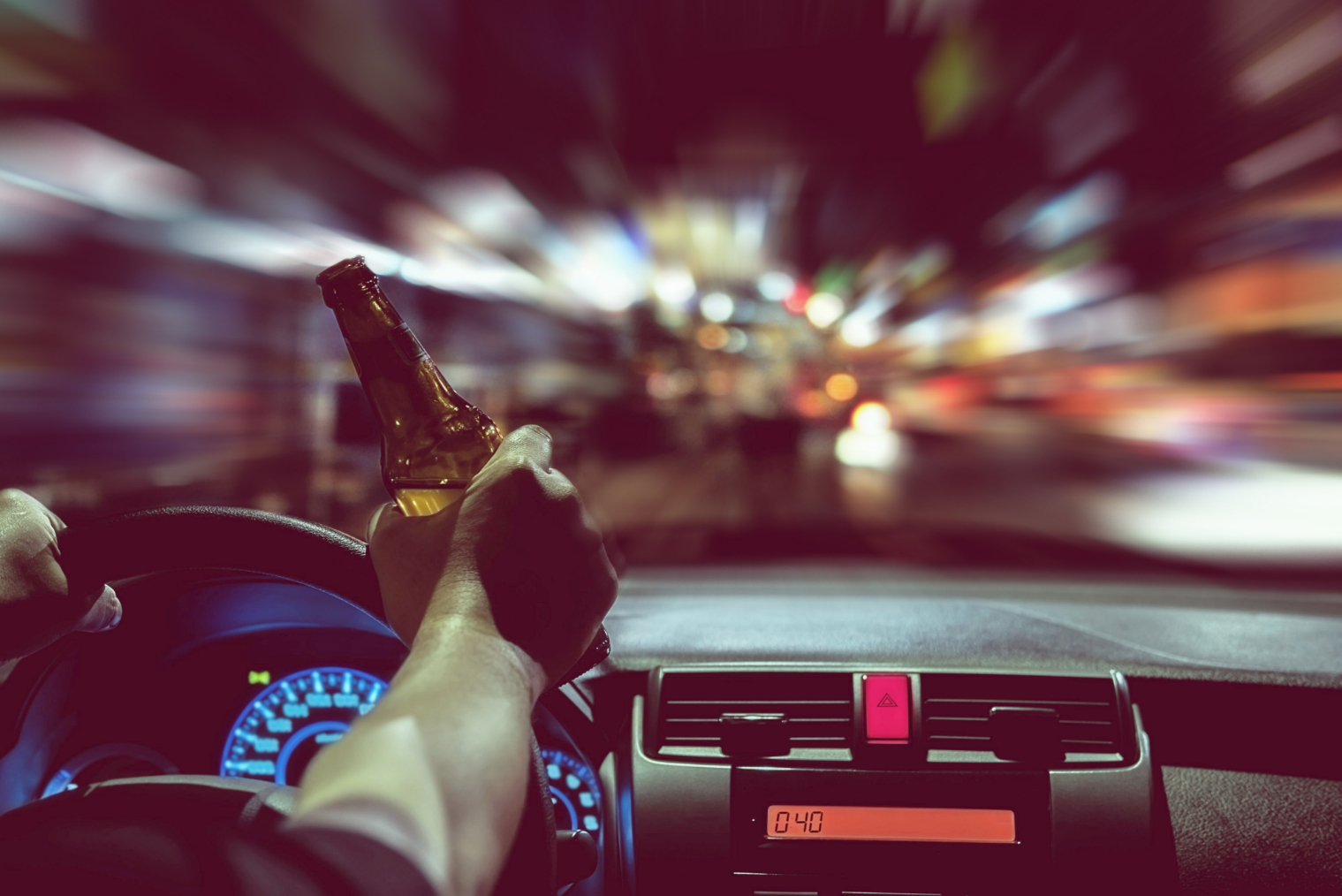 Man drink beer while driving at night in the city dangerously